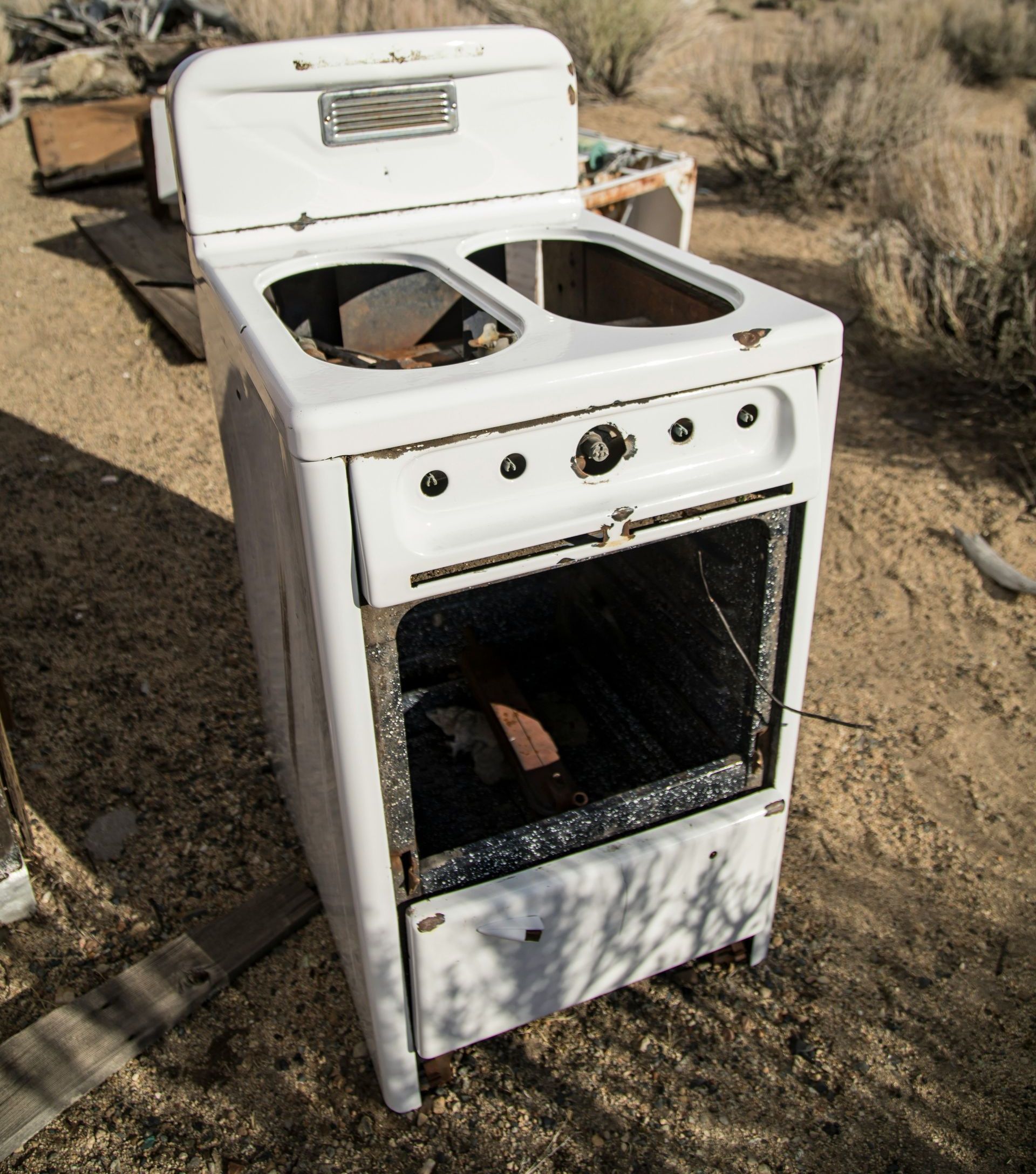 an old stove sitting in the middle of a dirt field